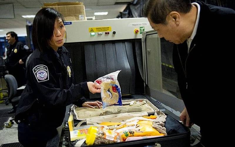 مامور فرودگاه در حال بازرسی چمدان یک مسافر