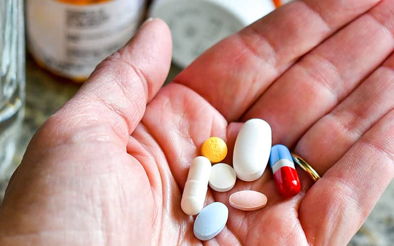 چندین قرص و کپسول در کف دست یک نفر