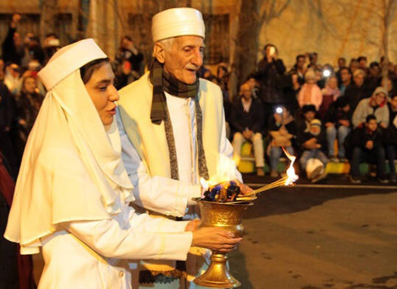 موبد زرتشتی و دختر سفیدپوش در حال روشن کردن آتش جشن سده