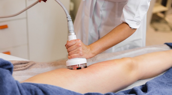 اپراتور در حال کار با دستگاه وکیوم تراپی روی بدن بیمار