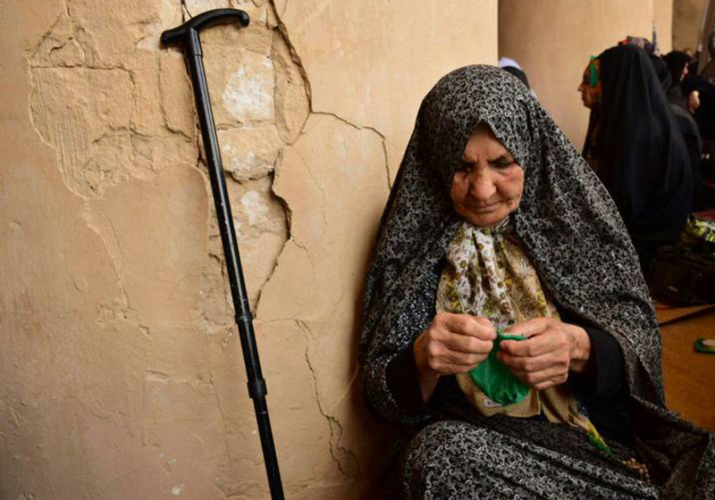 بانوی سالمند در حال کیسه دوزی