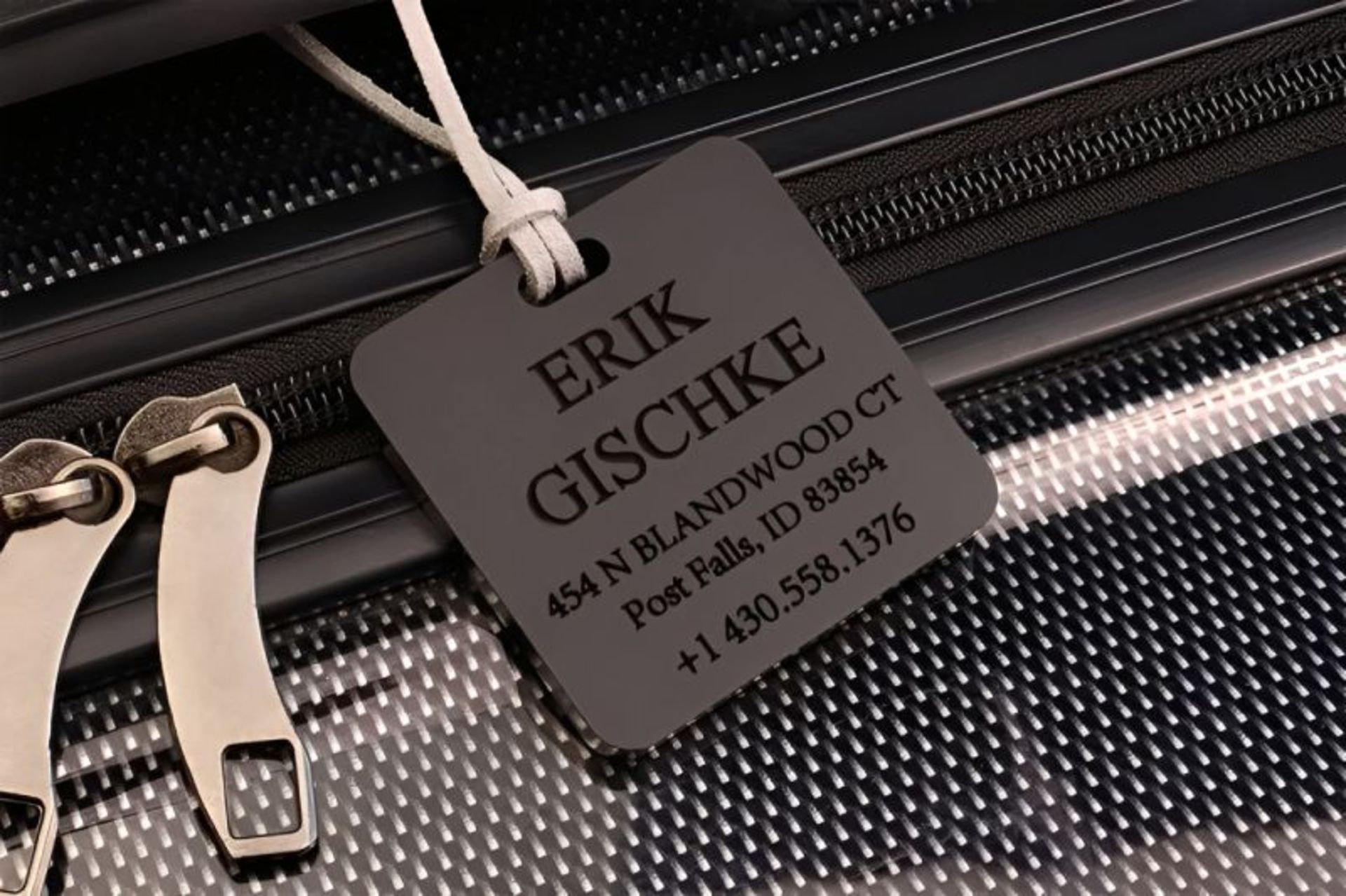 تگ مشخصات و اطلاعات فردی مشکی رنگ متصل شده به چمدان