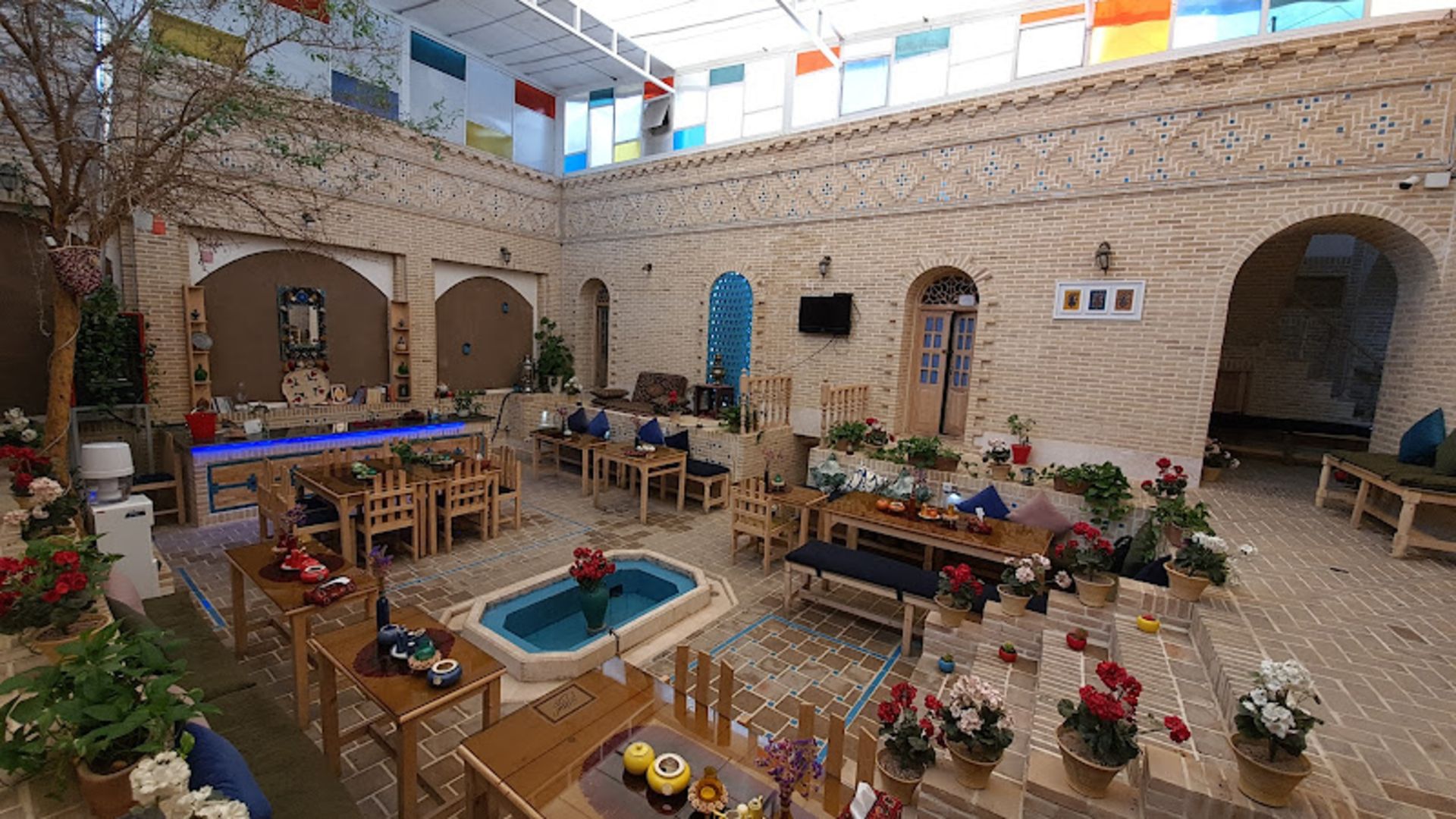 حیاط اقامتگاه سنتی شهباز کرمان با میز و صندلی های چوبی