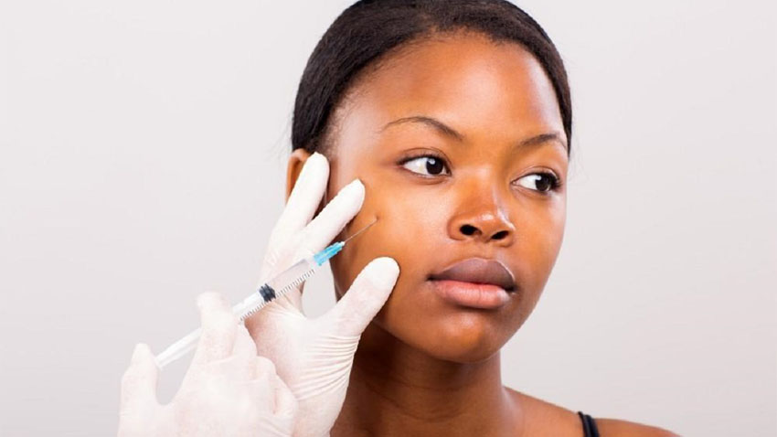 دختر سیاه پوستی که پزشک به گونه او فیلر تزریق می کند