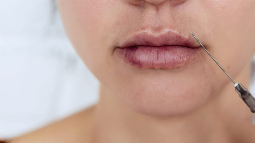 دختری که بالای لب او نوک سرنگ نگه داشته است و لب های او کبود شده است